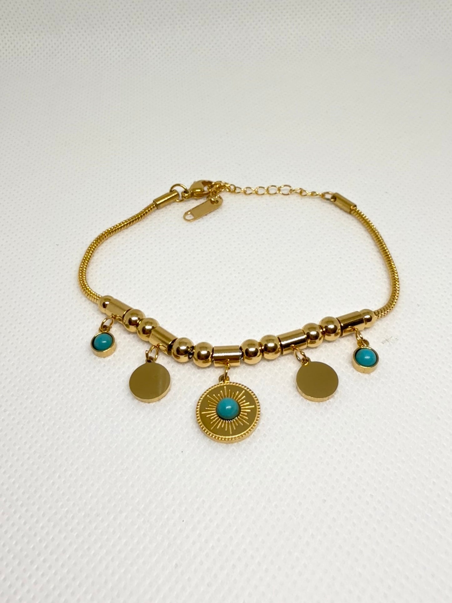 Gold bracelet with turquoise stones on a white background