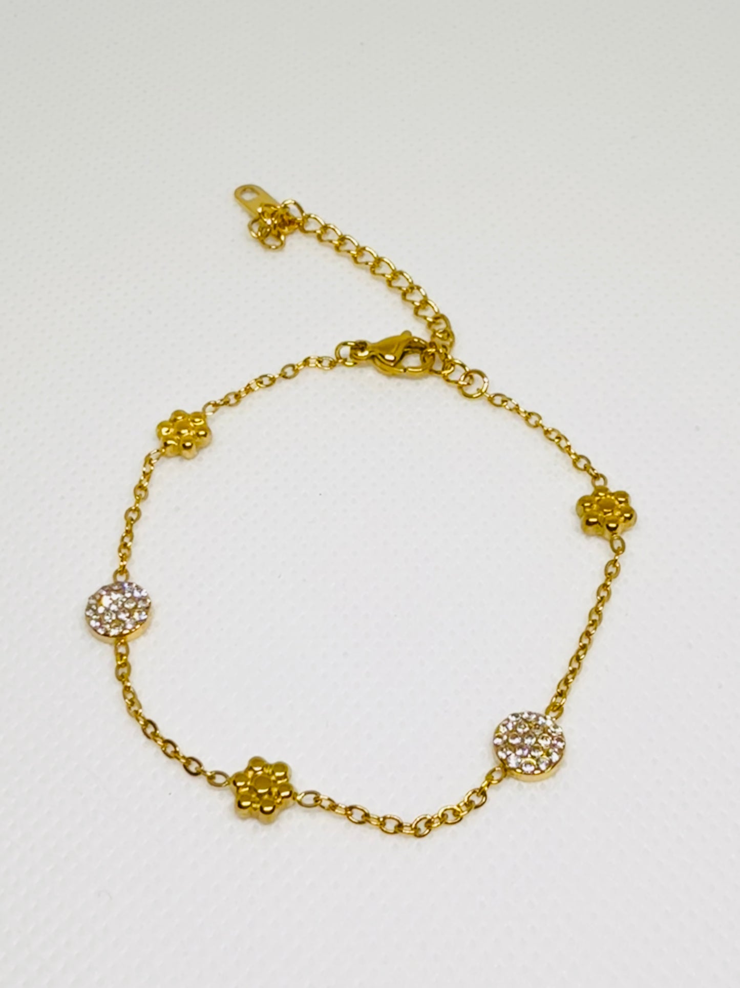 Gold bracelet with floral designs on a white background