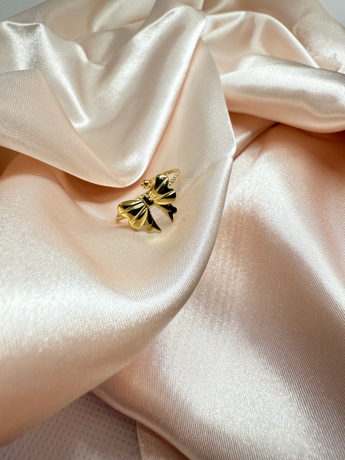 Gold butterfly-shaped brooch on a soft pink satin fabric