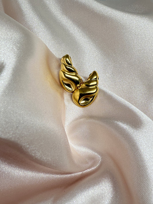 Gold earring on a white satin background