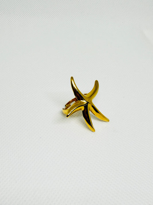 Gold starfish-shaped ring on a light gray background