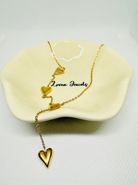 Gold heart-shaped necklace on a white stand with 'Lovera Jewels' branding.