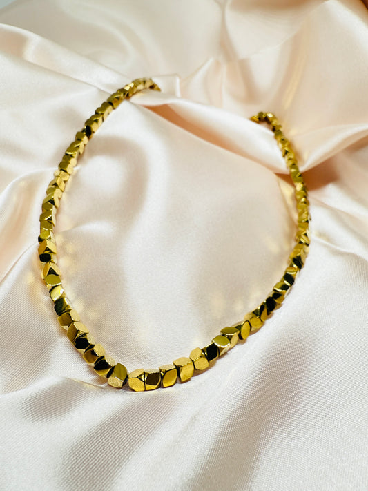 Gold necklace on a beige fabric background