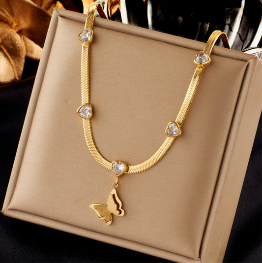 Gold necklace with butterfly pendant on a beige jewelry box